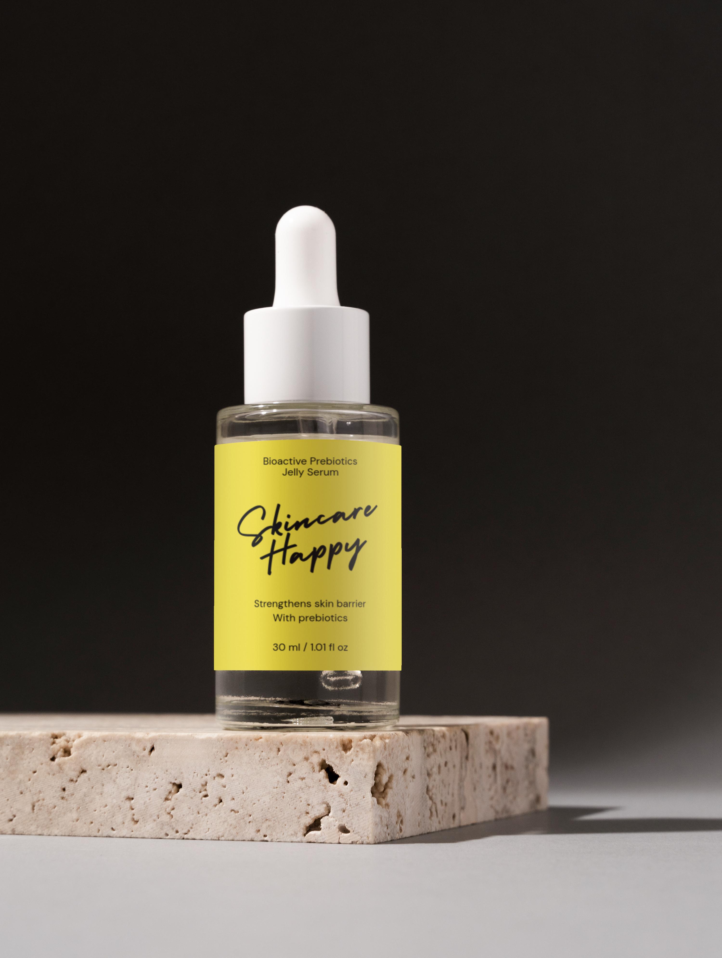 Skincare Happy dropper bottle on a stone platform with a black background