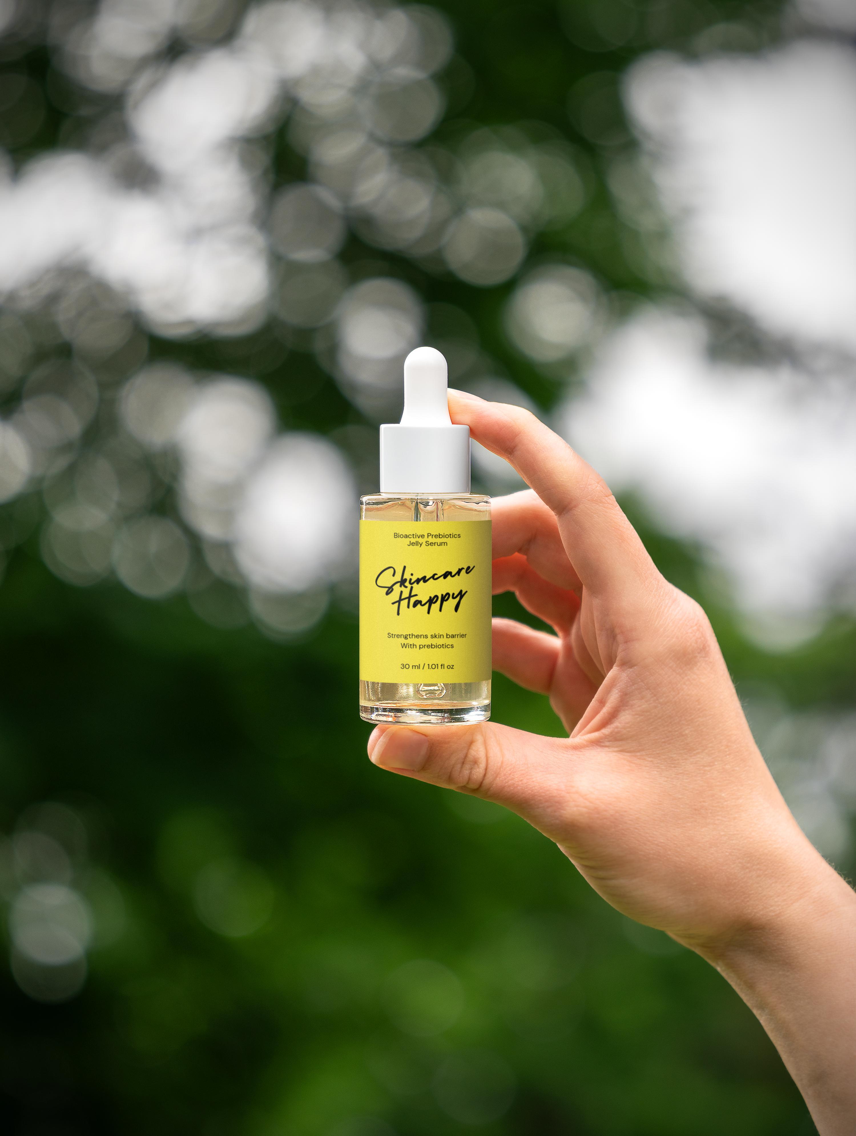 Hand holding a skincare product bottle with a blurred green background